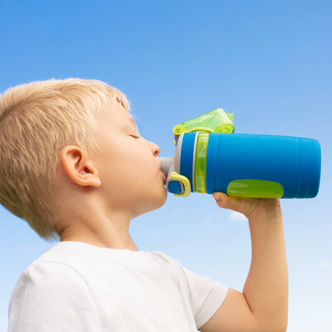 Enfant blond buvant dans une gourde bleu une boisson saine pour le goûter, de l'eau ou de la citronnade biobino