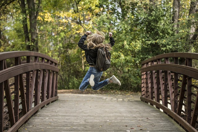 Un enfant qui saute de joie en allant à l'école car elle a dans son cartable un goûter Biobino qui est sain et naturelle à base de poudre de fruit biologique